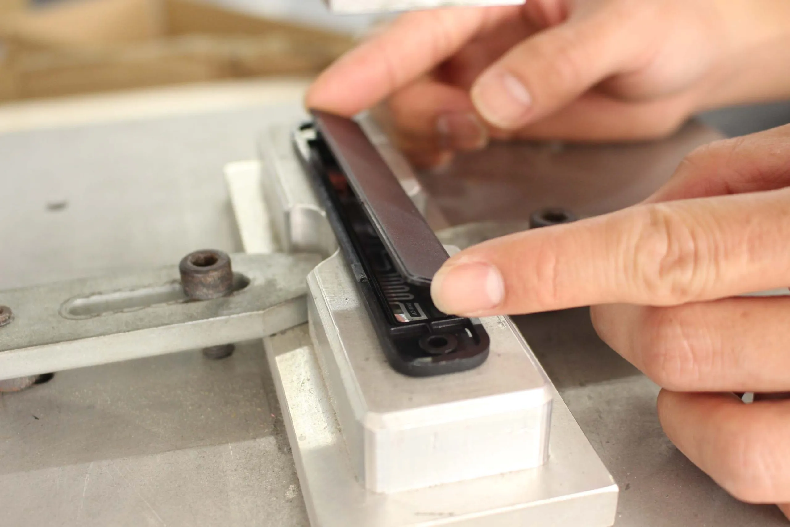 An RFID inlay seated in a rigid tag housing with a fixing hole, with the cover being pressed on over it on an assembly jig